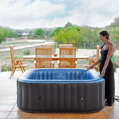 Woman filling Tekapo inflatable hot tub with water on back porch