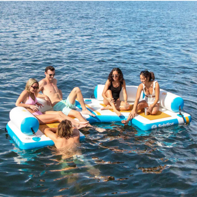 Five adults hanging out on Solstice C Dock inflatable lounger in water