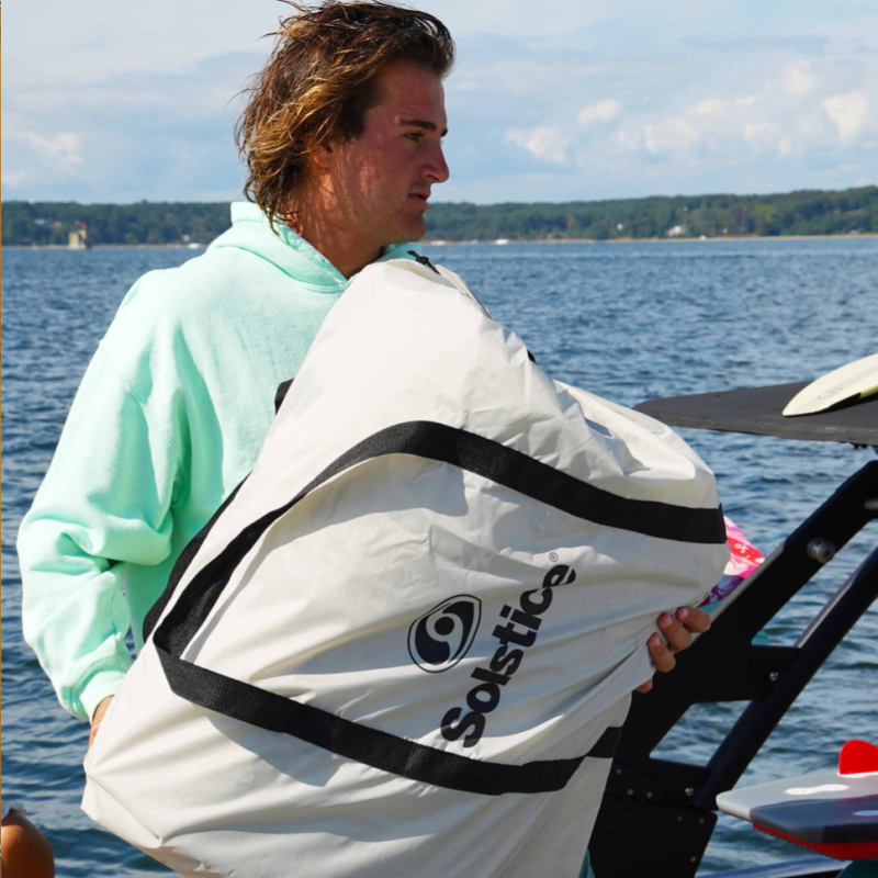 Guy holding Solstice Solstice 10'x8' Inflatable Dock in carrying bag on his boat