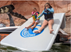 Two kids sliding  down the Slide Island Inflatable slide dock by Lakesurf