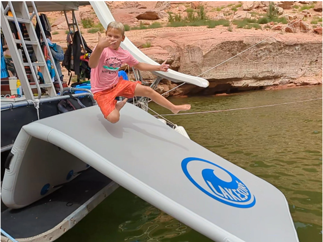Young boy jumping onto his new Lakesurf-Slide Island inflatable Slide Dock Combo